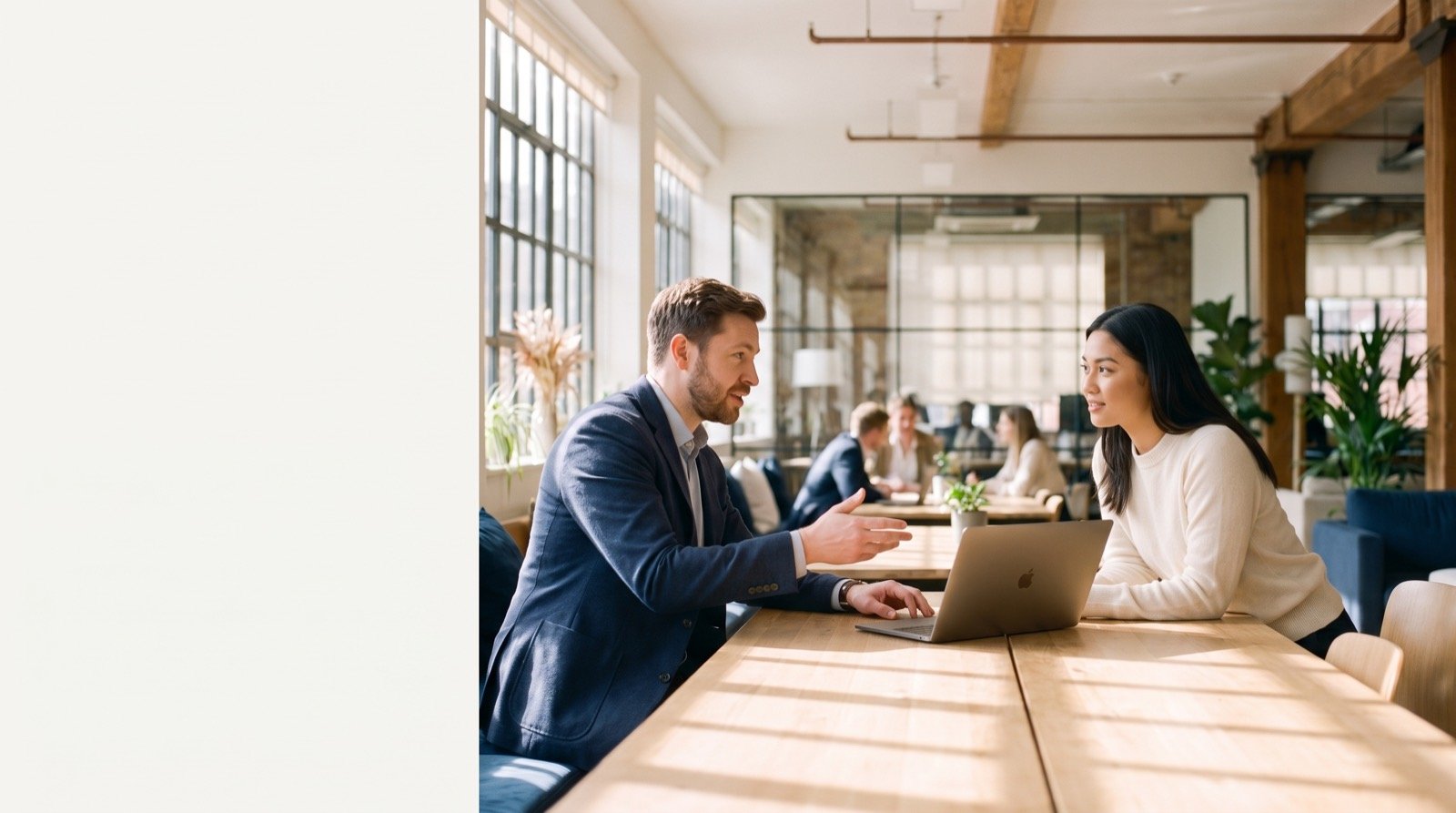 Two consultants in conversation over a laptop in a bright, warm-lit office
